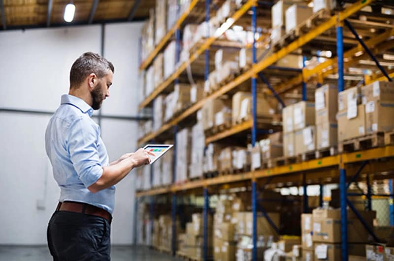Man using tablet in warehouse setting - Warehouse Management Expertise